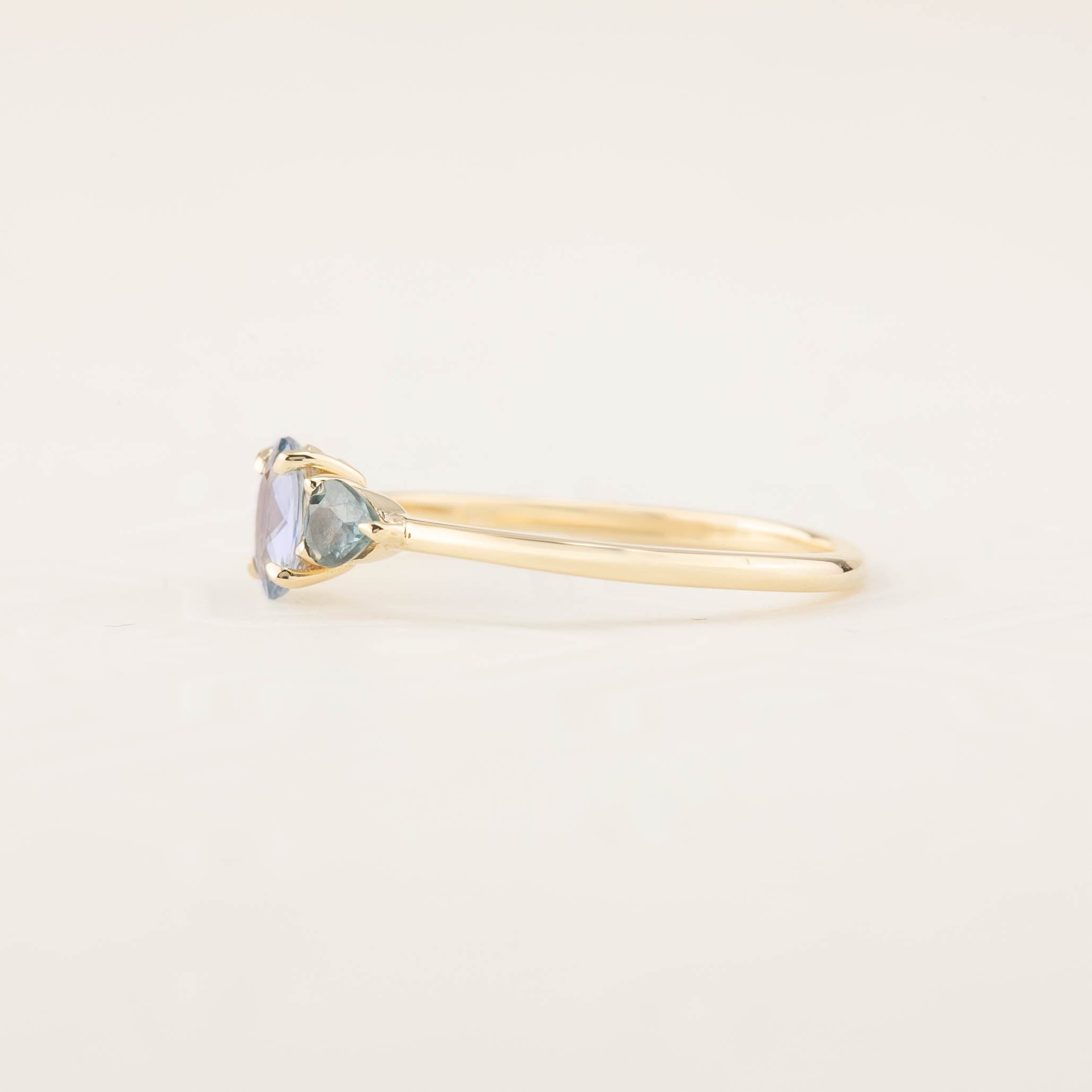 Side view of one-of-a-kind blue sapphire three stone ring with recycled 14k gold prong setting