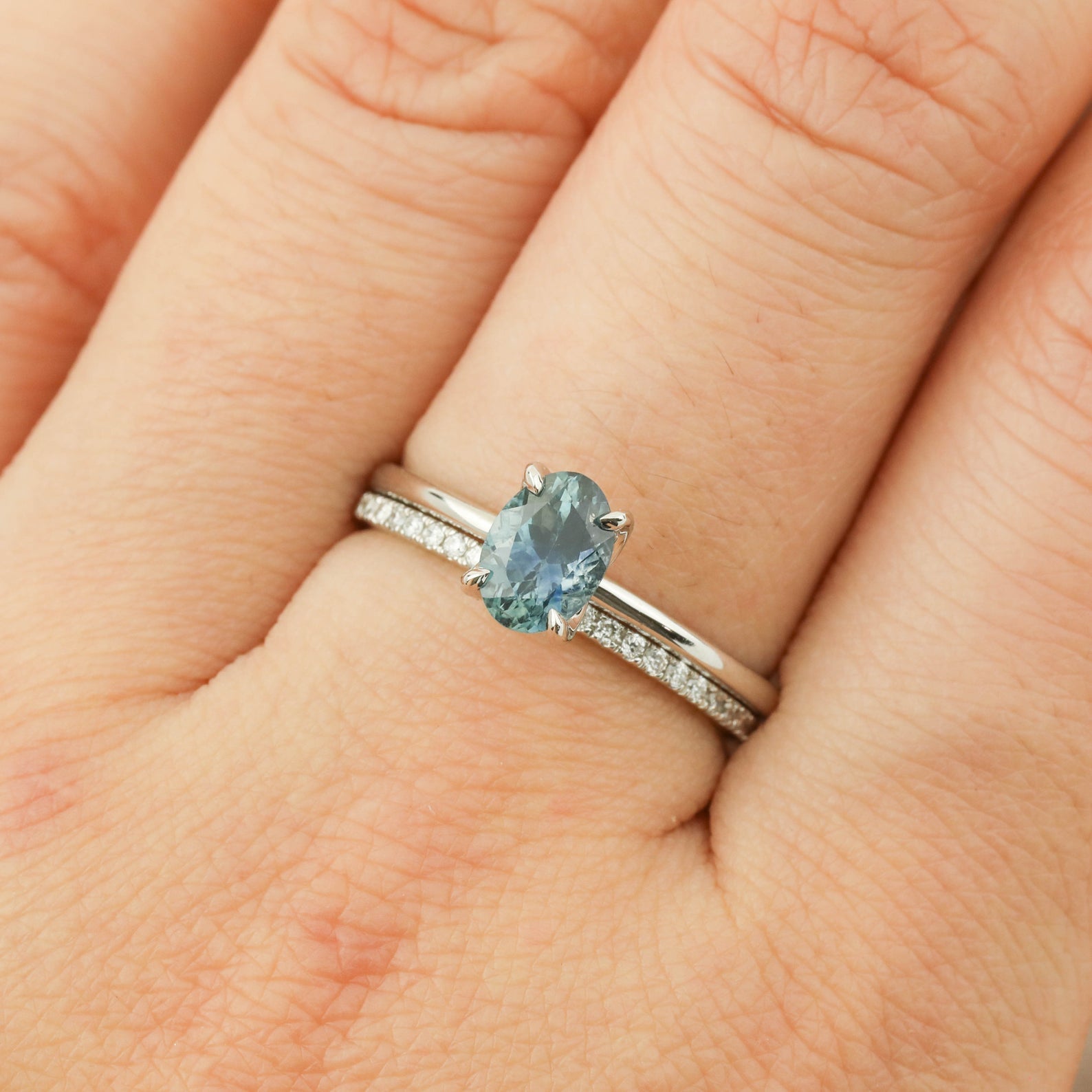 Close-up of a 1.00ct parti blue green Montana sapphire ring set in 14k white gold on a hand.