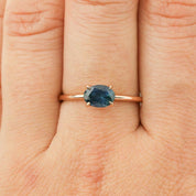Close-up of a 1.00ct green Montana sapphire ring in 14k rose gold on a finger with a delicate tapered band.
