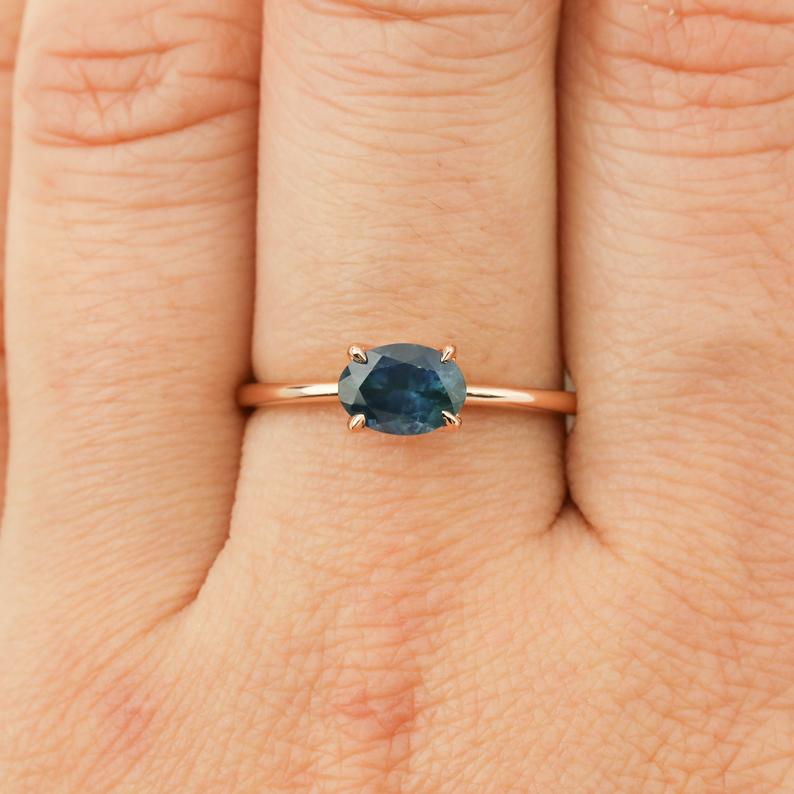 Close-up of a 1.00ct green Montana sapphire ring in 14k rose gold on a finger with a delicate tapered band.