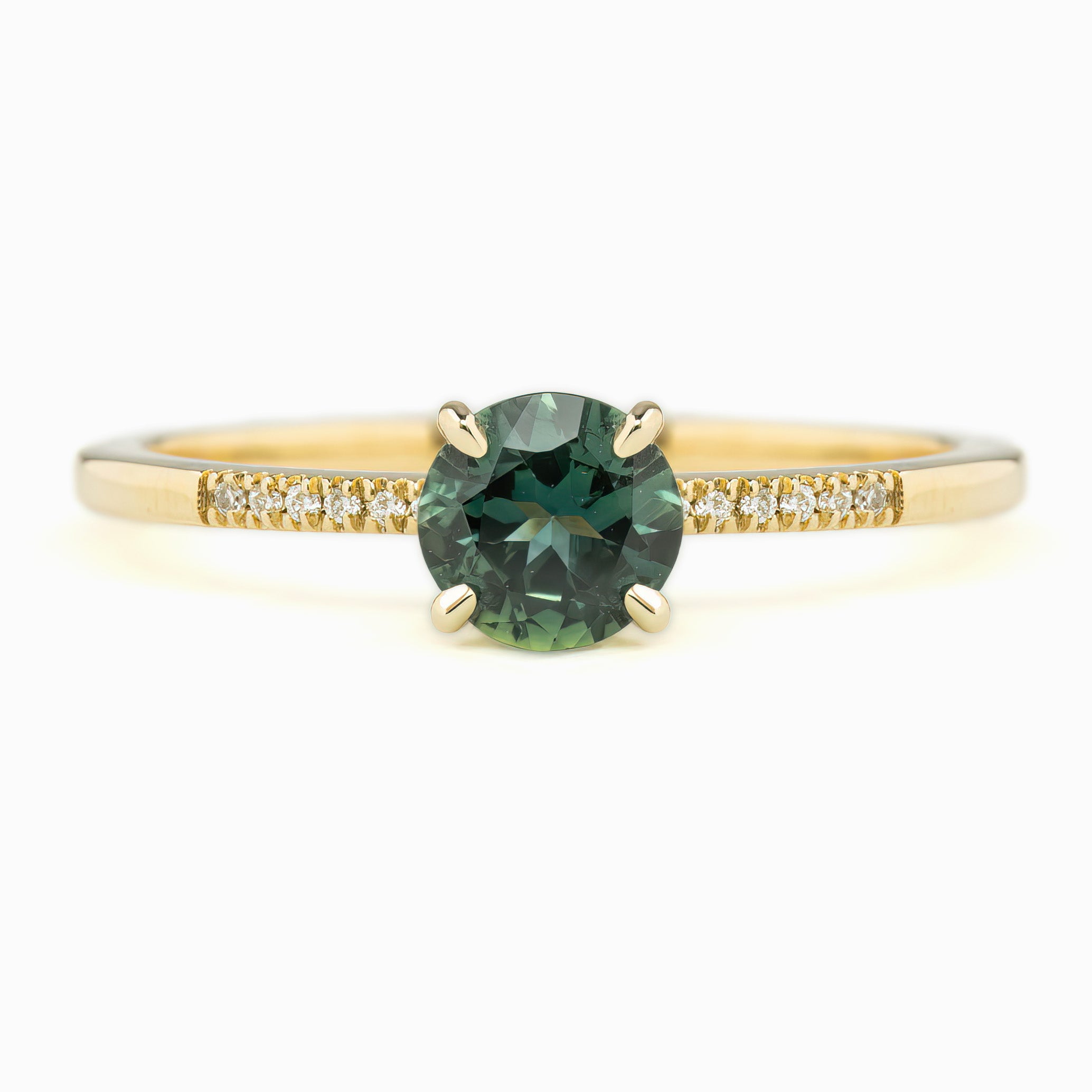 Audrey Ring with a 0.73ct Teal Blue Queensland Sapphire center stone, set in a 14K Yellow Gold band with small diamond accents.