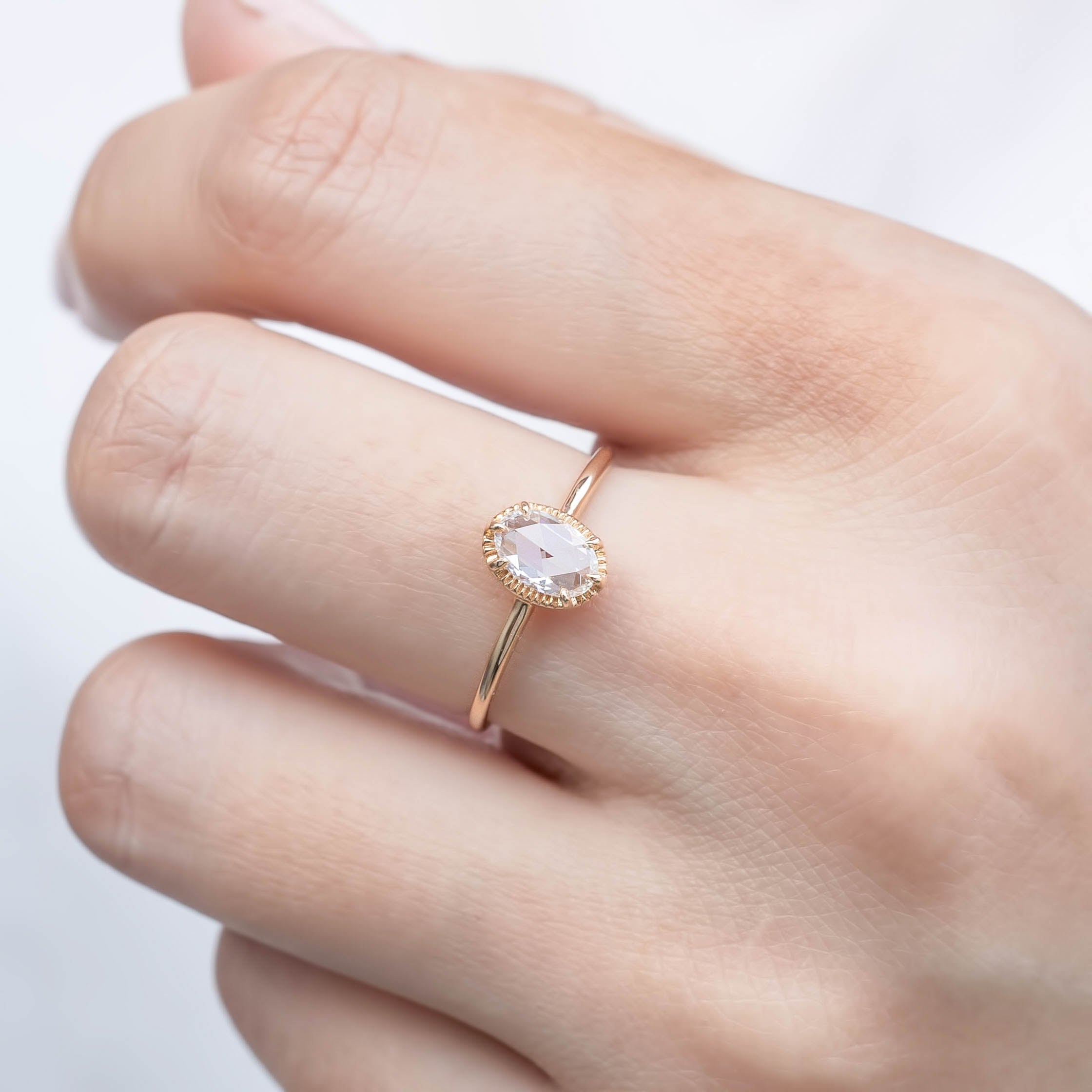 Close-up of hand wearing Ava Ring with 6x4mm oval rose cut diamond set in a tapered rose gold band