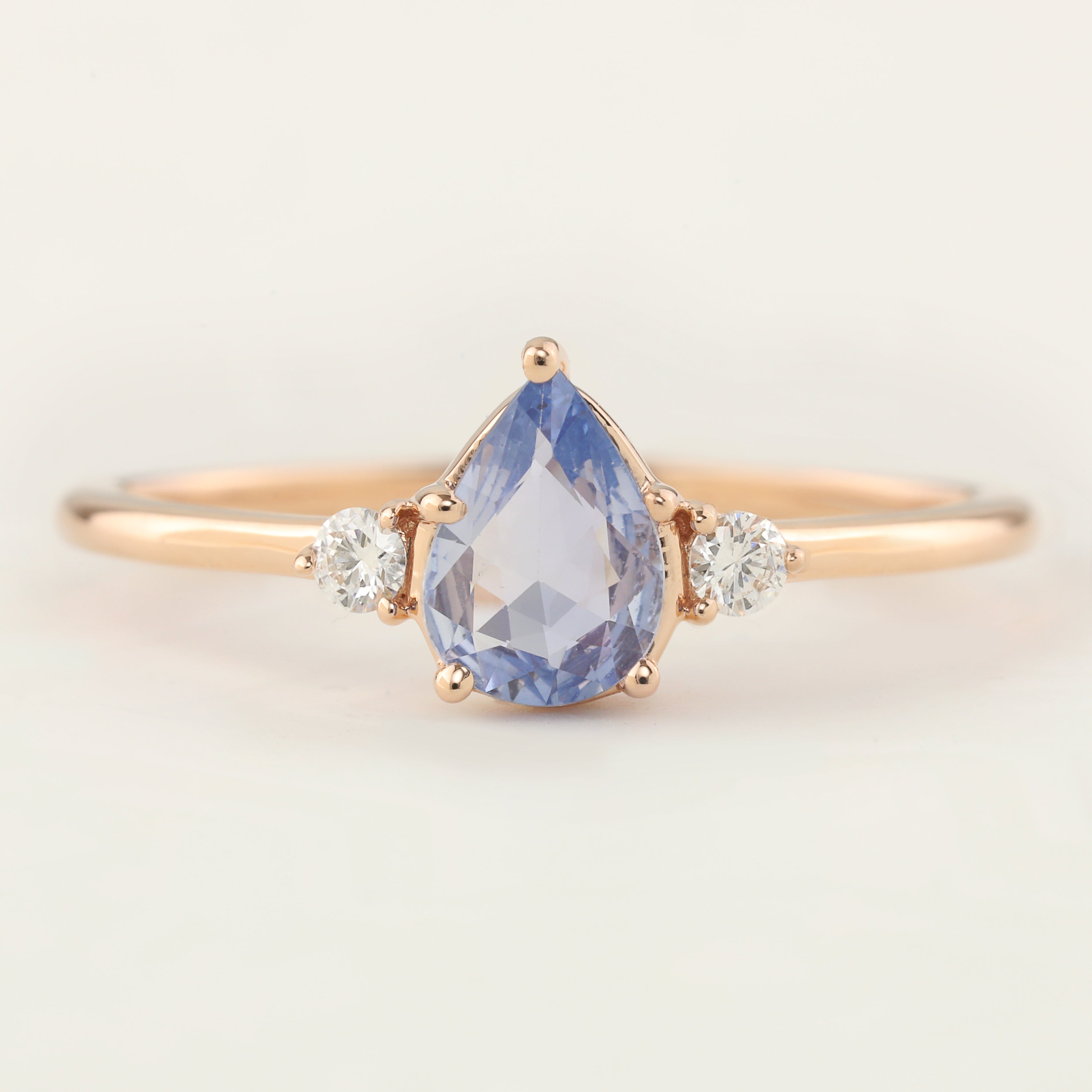 Stunning Emilie Ring featuring a teardrop-shaped unheated blue sapphire and sparkling accent diamonds in 14k rose gold.