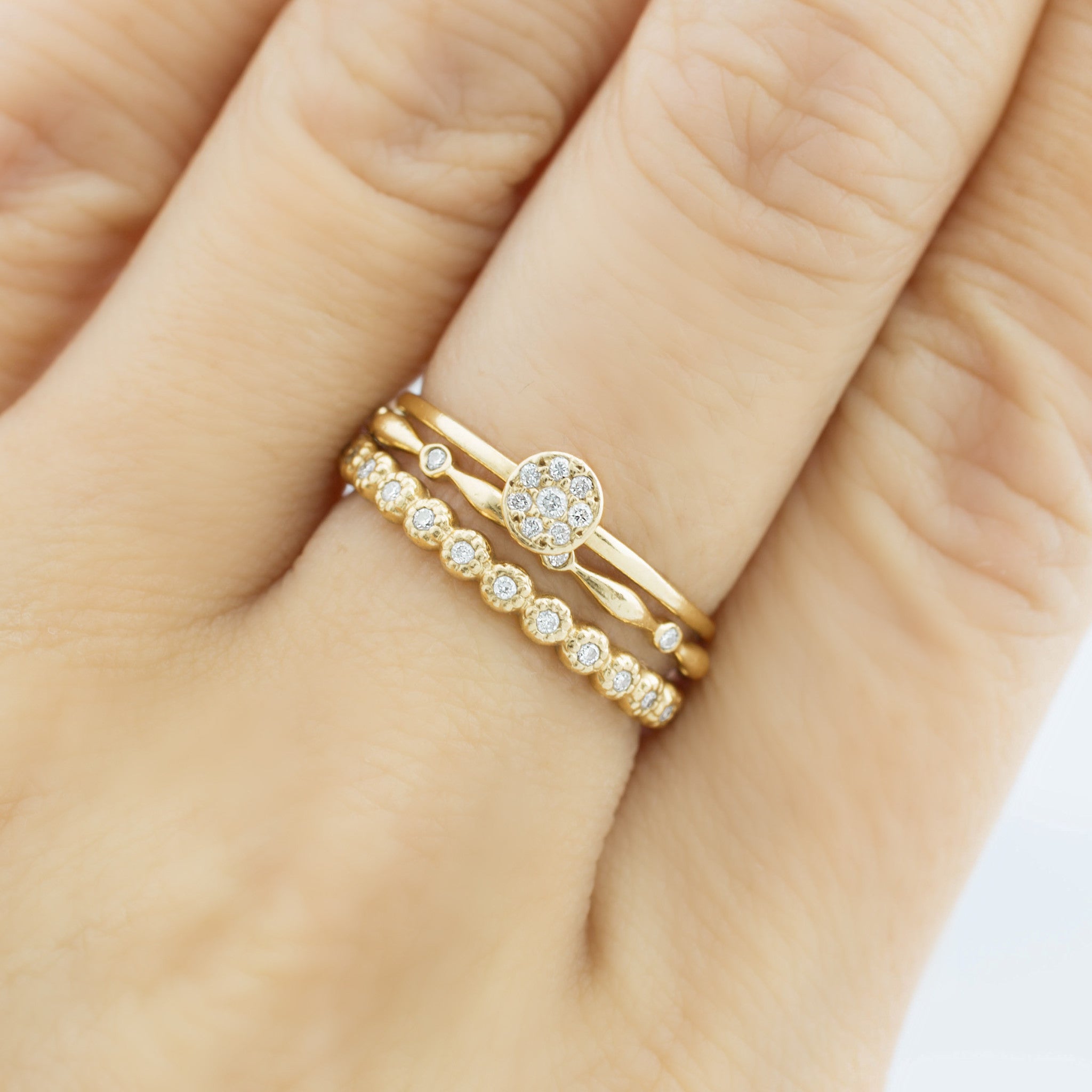 Close-up of a hand wearing a gold Aria Eternity Ring with natural white diamonds in a full-eternity design