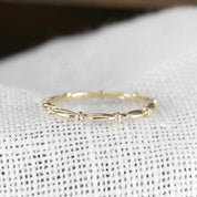 Ethically sourced solid gold Julia Ring with full eternity bead design and 1.7mm band width on textured fabric background