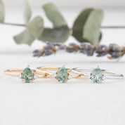 Three gold rings with pear-shaped green sapphire in 14k yellow gold, rose gold and white gold
