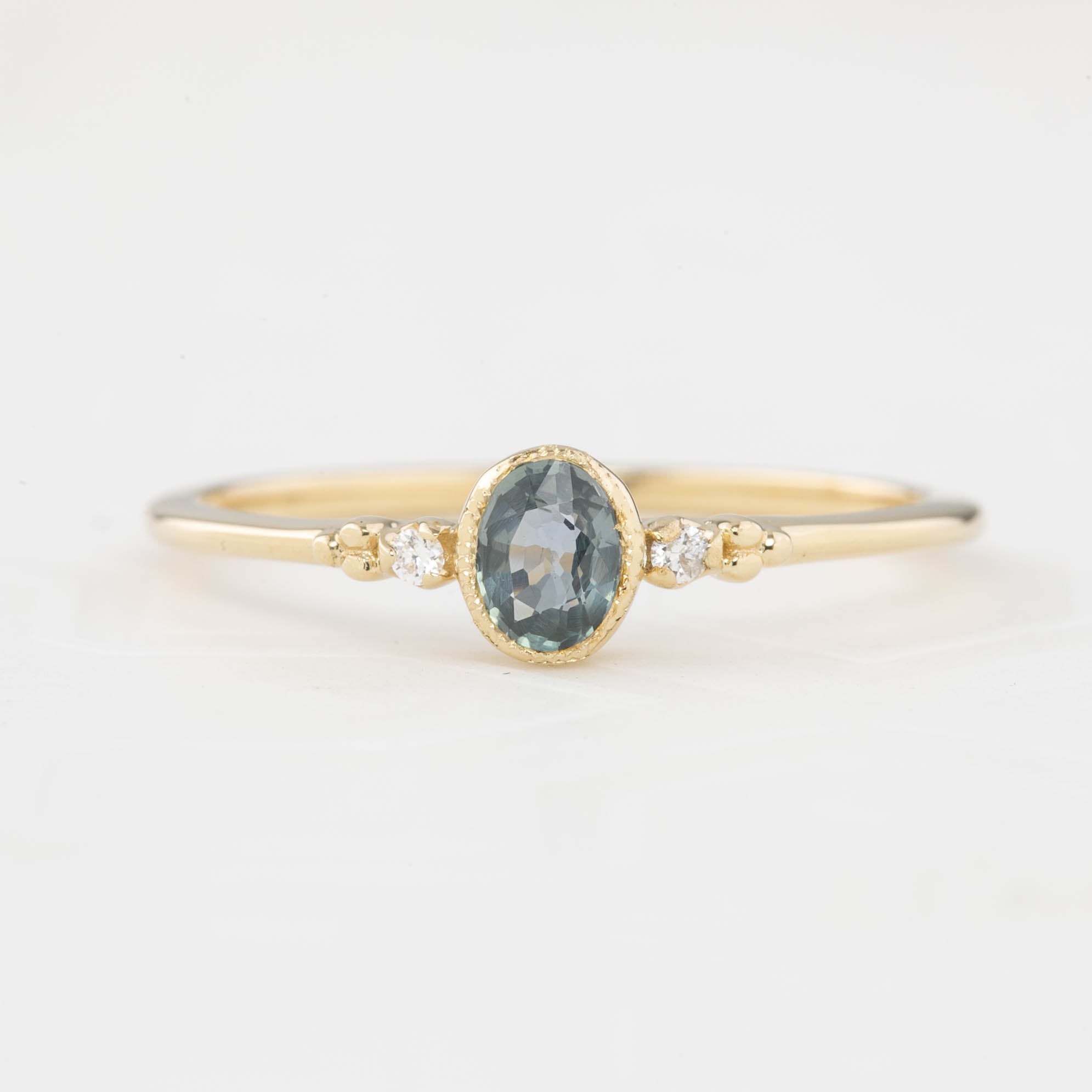 Bezel set oval Madagascar sapphire ring with two natural diamond accents in a low profile 14k gold setting.