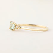 Side view of Estel ring with 0.5ct radiant cut mint tourmaline and small diamonds in 14k yellow gold band