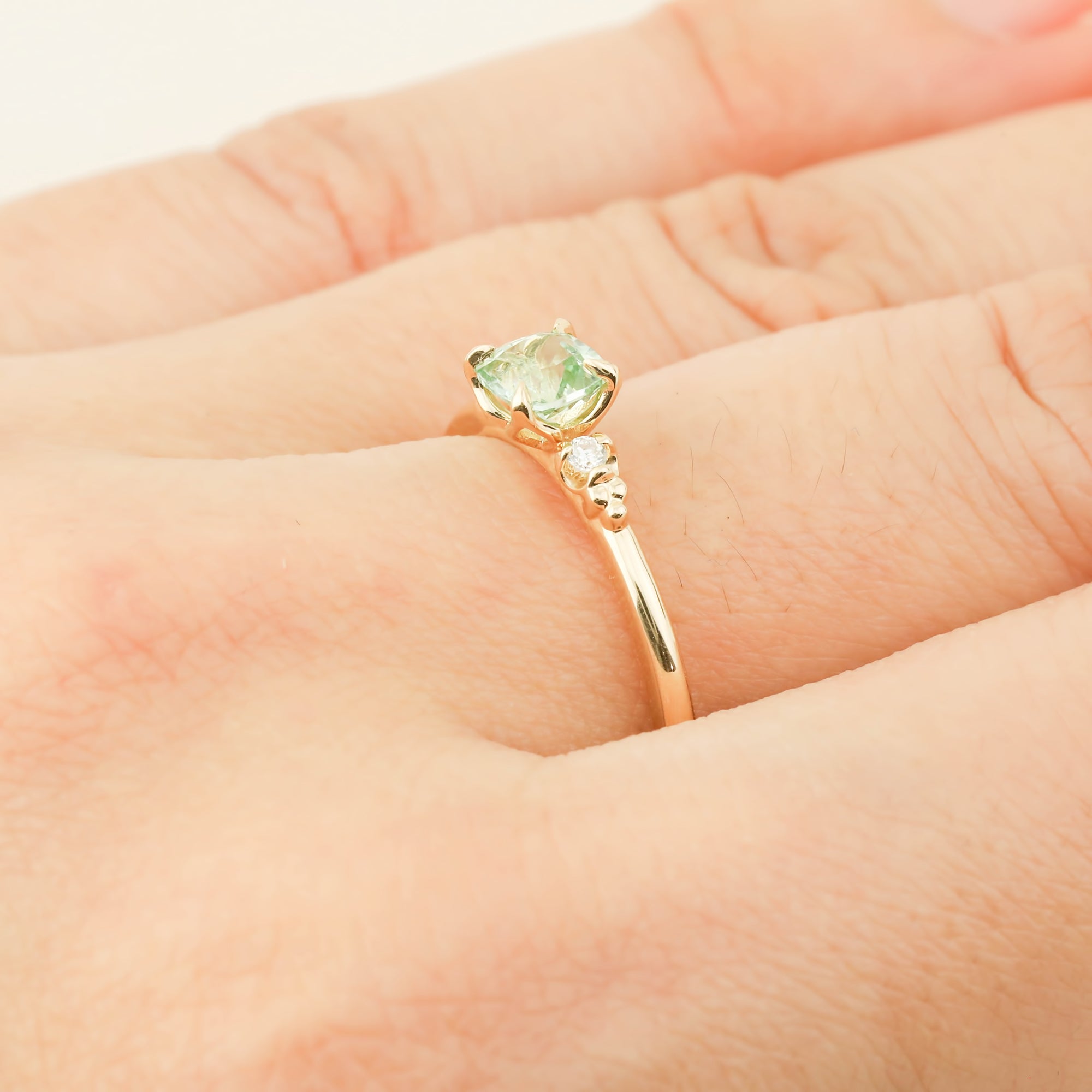 Close-up of Estel ring with 0.5ct radiant cut mint tourmaline in 14k yellow gold on finger