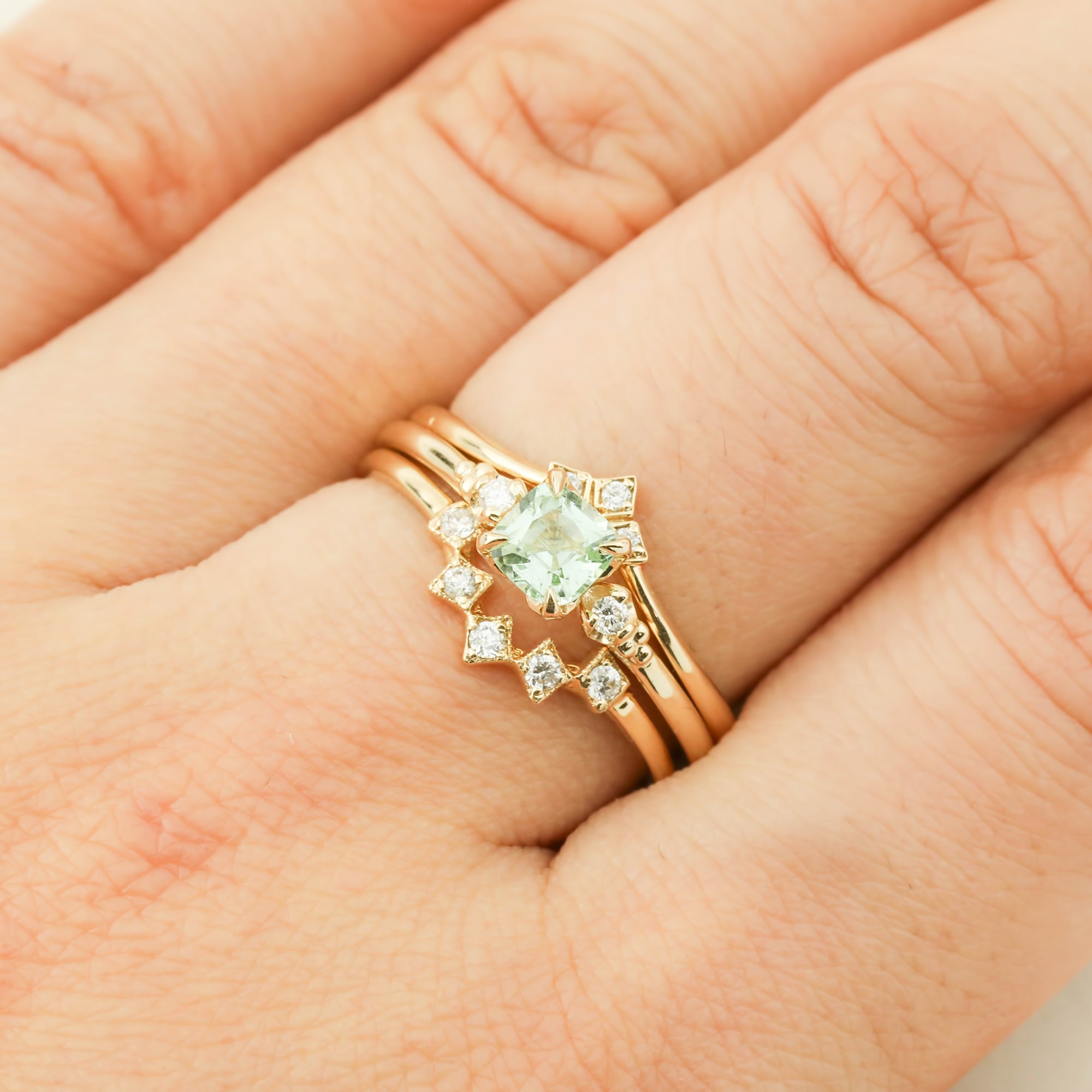 Hand wearing resizable 14k yellow gold Estel Ring with 0.5ct radiant cut mint tourmaline and diamond accents