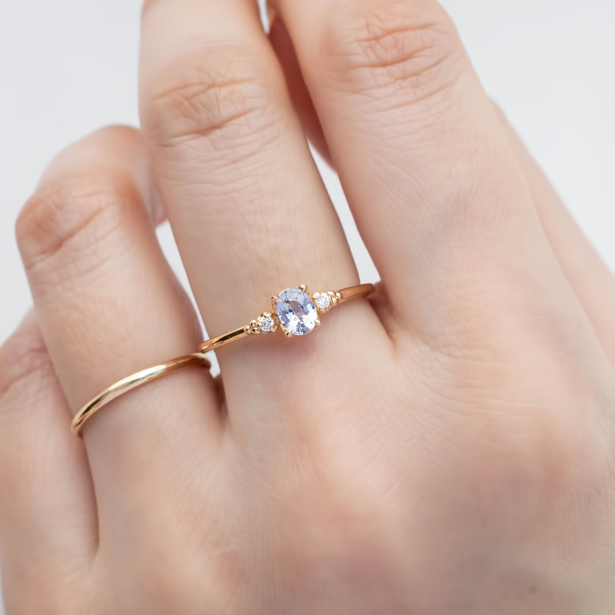 Estel Ring featuring a 0.40ct light blue unheated oval sapphire and 14k yellow gold diamond accents on a finger