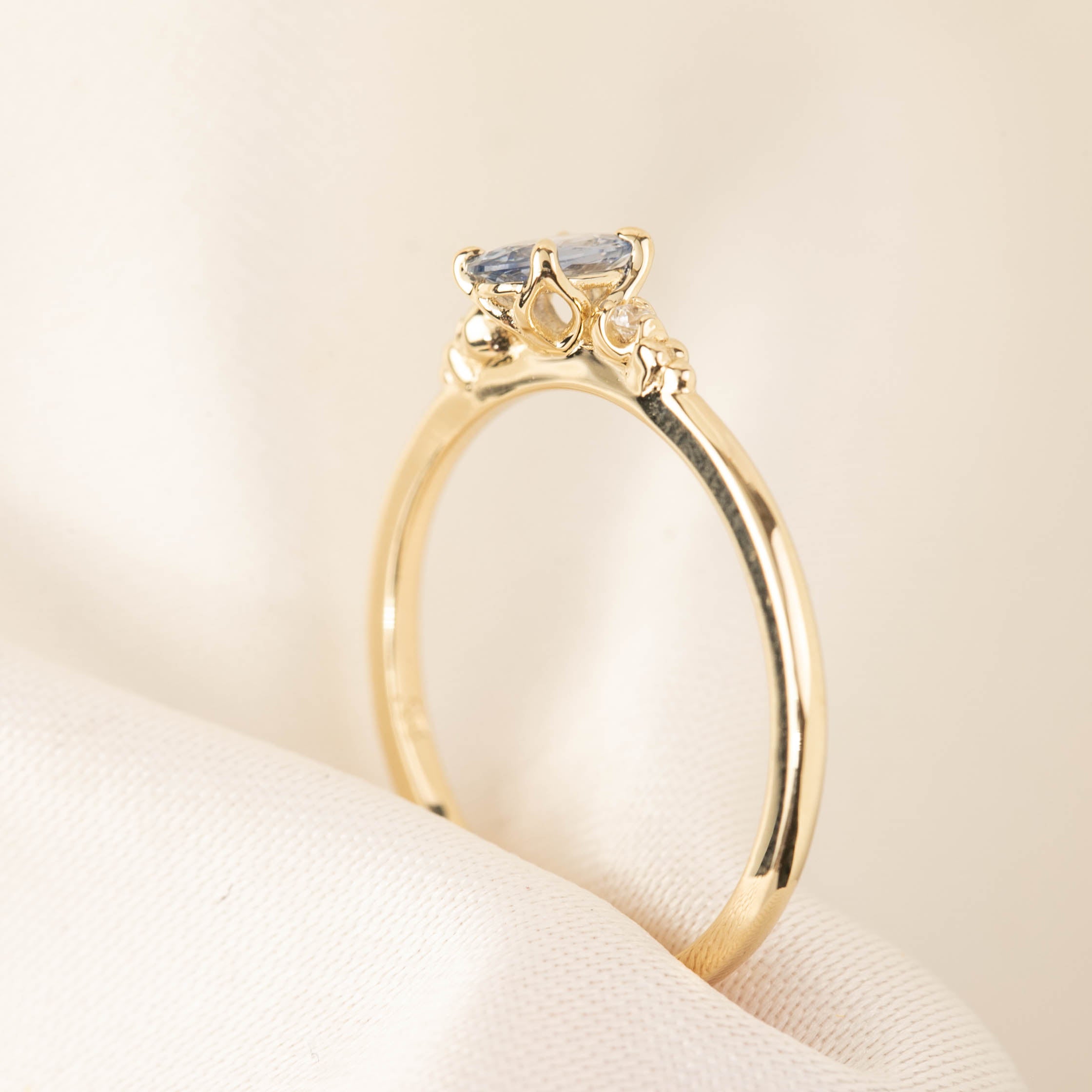 Three 'Estel Rings' with oval-shaped sapphires, in settings of 14k rose gold, 14k white gold, and 14k yellow gold, displayed against a light background., oval shape gemstone