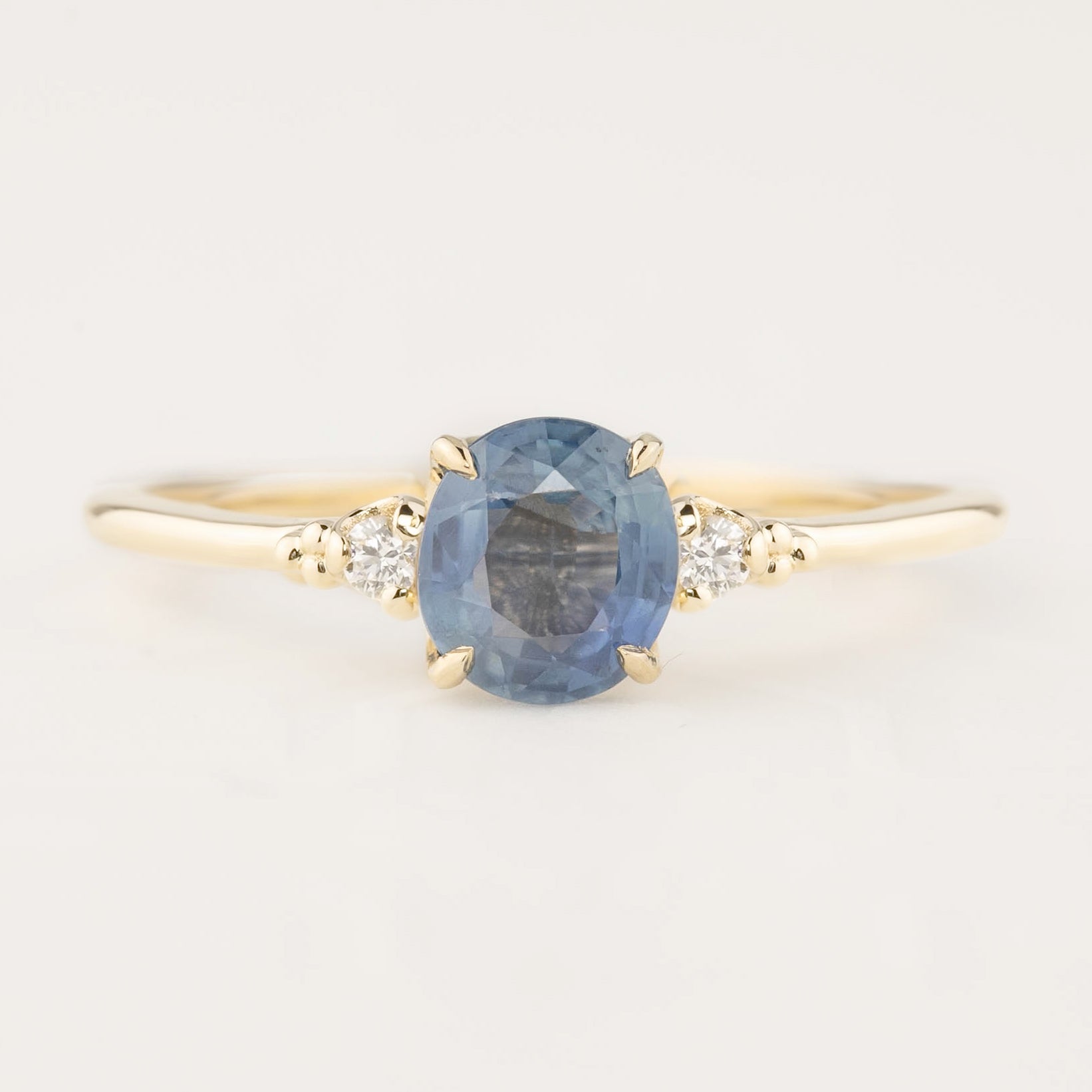 14k gold ring with 1.25ct blue sapphire and two small white diamond accents in flower setting
