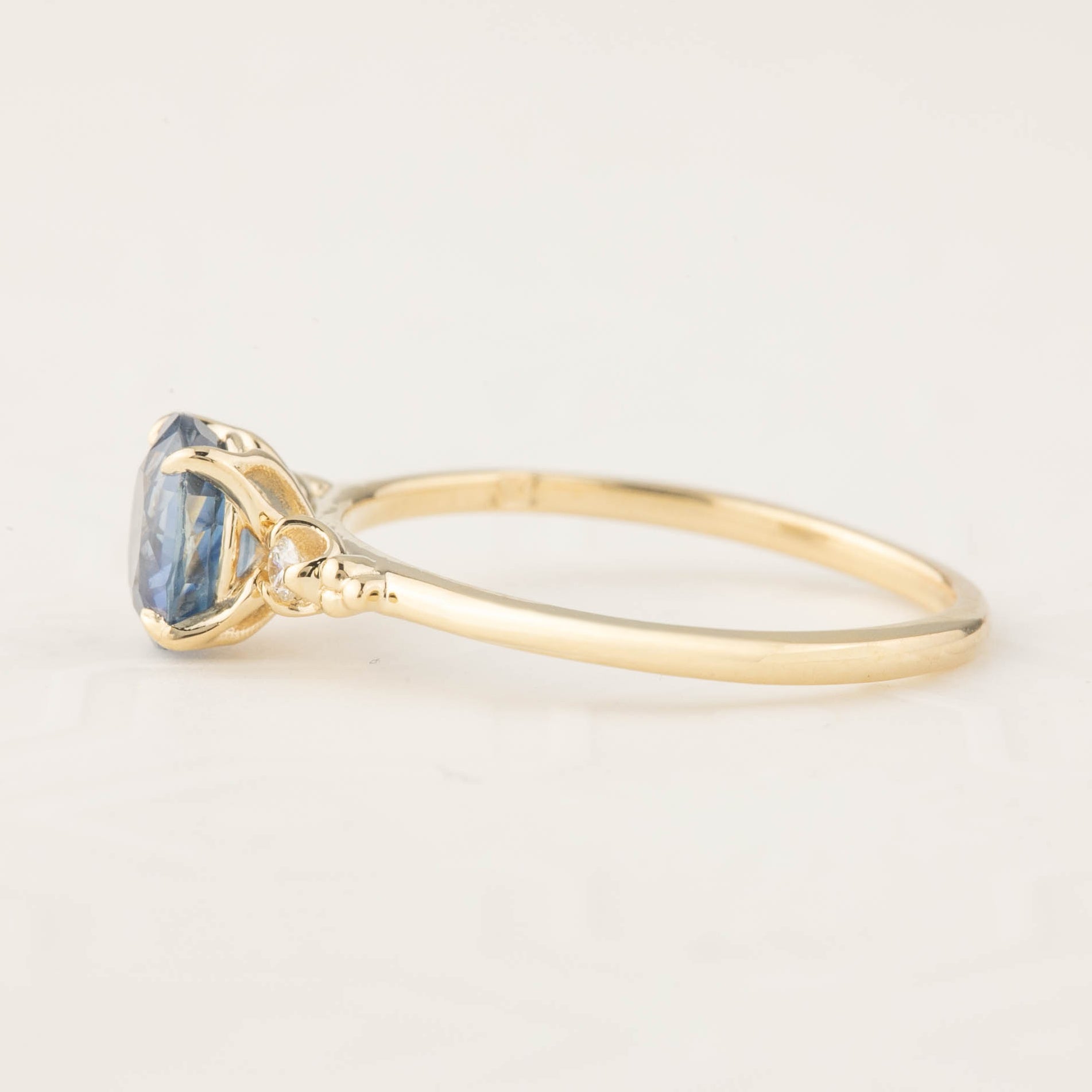Side view of Estel Ring with 1.25ct blue sapphire and diamond accents set in recycled 14k gold band.