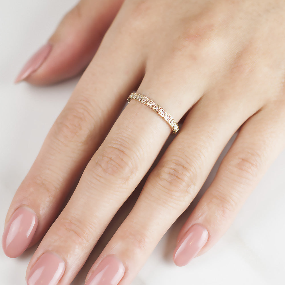 Close-up of a hand wearing a delicate Hazel Eternity Ring with natural white diamonds on a gold band