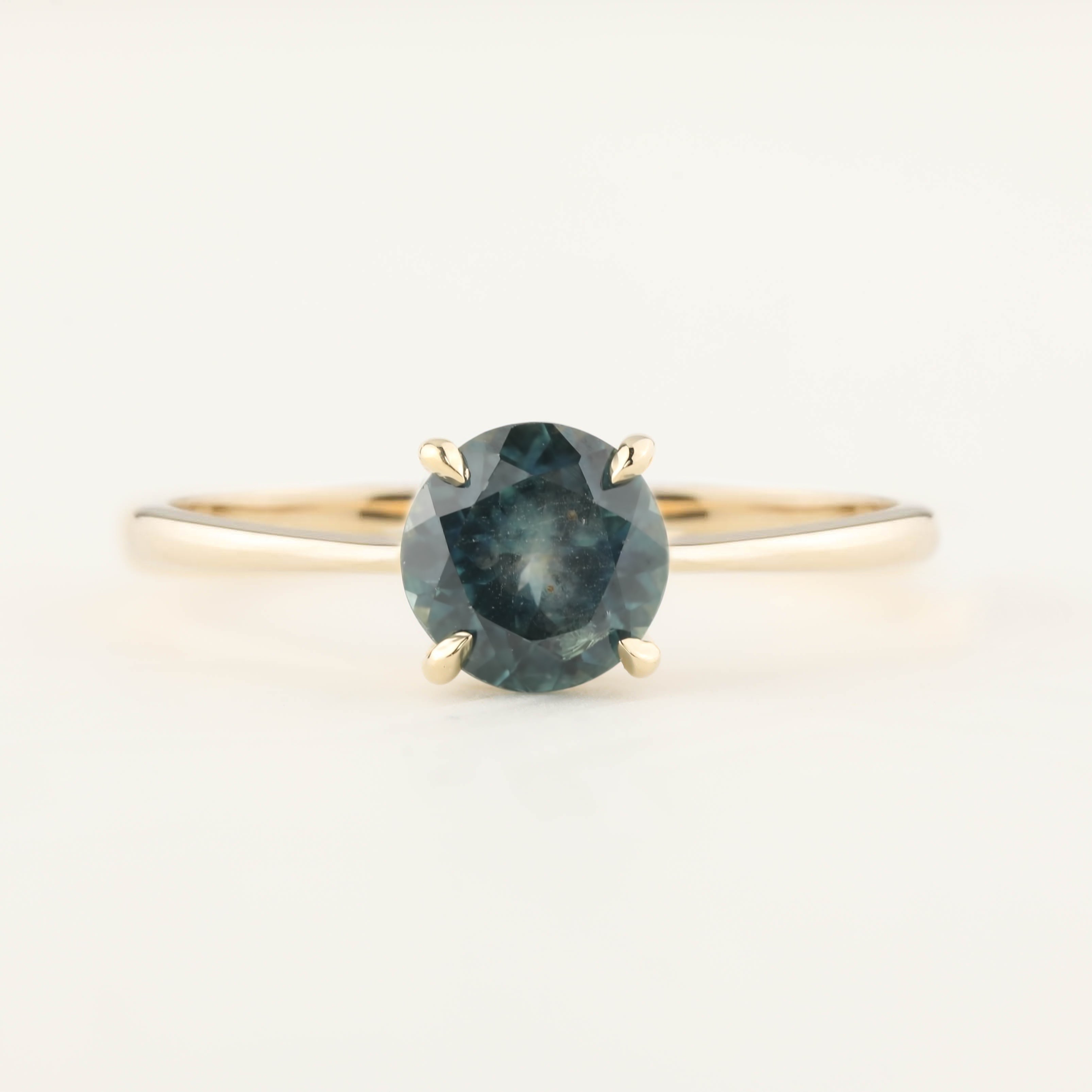 Close-up of Nina Ring featuring 0.94ct teal blue Montana sapphire set in 14k yellow gold tapered band