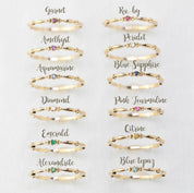 Twelve 14k gold birthstone rings including ruby, sapphire, emerald, diamond, garnet, amethyst, and others in size 7 displayed on white background.