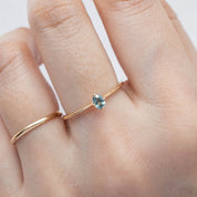 Close-up of a natural blue-green oval sapphire showing the unique unheated color 14k yellow gold ring on a hand