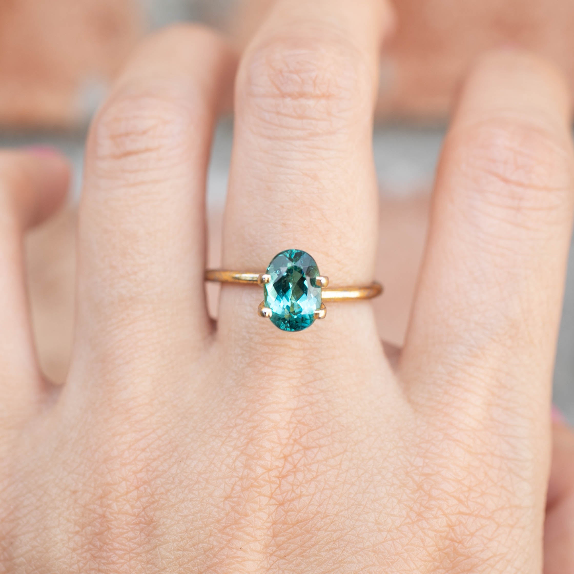 Oval cut 1.76ct green tourmaline ring set in gold, worn on finger with bright emerald green color