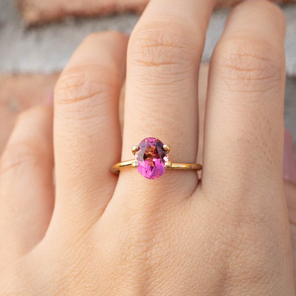 1.71ct Oval Cut Pink Tourmaline ring on hand, featuring a vibrant pink gemstone set in a delicate gold band.